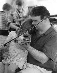 Kid with fiddle on dad's lap