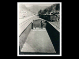 Two men cleaning a coal car on railroad tracks, mine Number 254. Other cars, houses, and church are in the background. This picture is also found in the DeHaven Collection, Roll 1610 02.