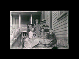 Woman and six children sitting with dog on the steps of lower house at Nuttalburg.