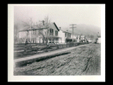 Electro Metallurgical Company houses on Main Street (dirt road) in Glen Ferris. Wood fence along road. Horse and wagon in distance.