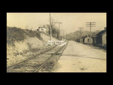 Car track and Main Street of Reynoldsville. Row of one- story frame houses.