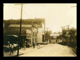 Street scene in Fairview with Good Roads Meeting banner. Brick street.